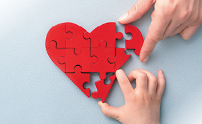 The concept of charity, love, donate and helping hand. International cardiology day. A woman and child arranges red heart shape puzzles. Symbol of helping others.